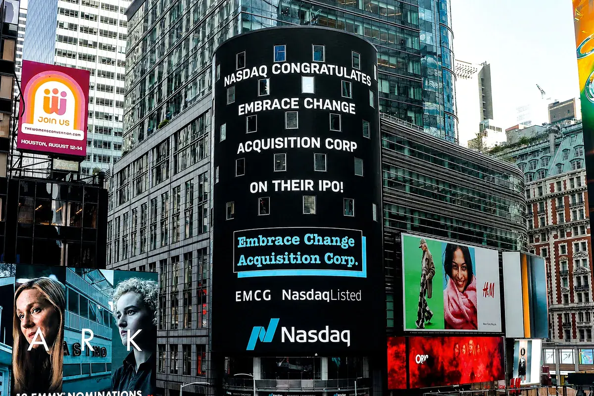 The Nasdaq MarketSite tower in Times Square displaying 'Nasdaq congratulates Embrace Change Acquisition Corp on their IPO', with the EMCG ticker.