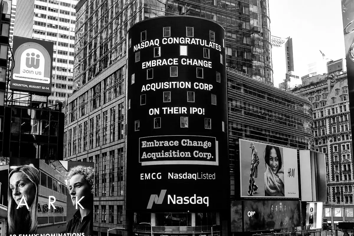 The Nasdaq MarketSite tower in Times Square displaying 'Nasdaq congratulates Embrace Change Acquisition Corp on their IPO', with the EMCG ticker.